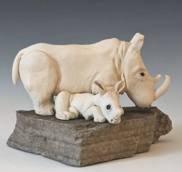 Sculpture of a rhinoceros and its calf on a rock base.