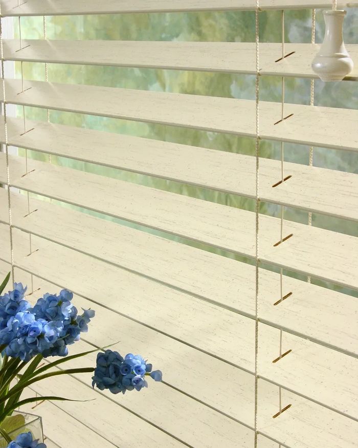 Wood slate blinds with blue flowers in the foreground 