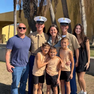 A happy family posing outdoors with two Marines in uniform.