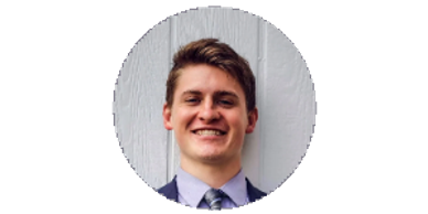 Smiling young man in suit against white wooden background.