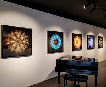 5 larger circular photos on black backgrounds in a gallery in front of a grand piano