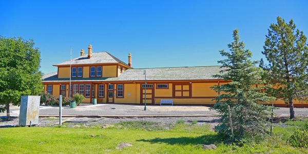 Historic yellow train station building under clear blue sky.