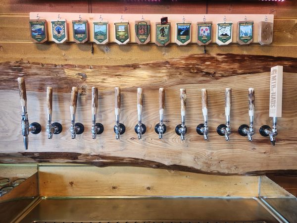 Row of wooden beer taps mounted on a light wood slab.