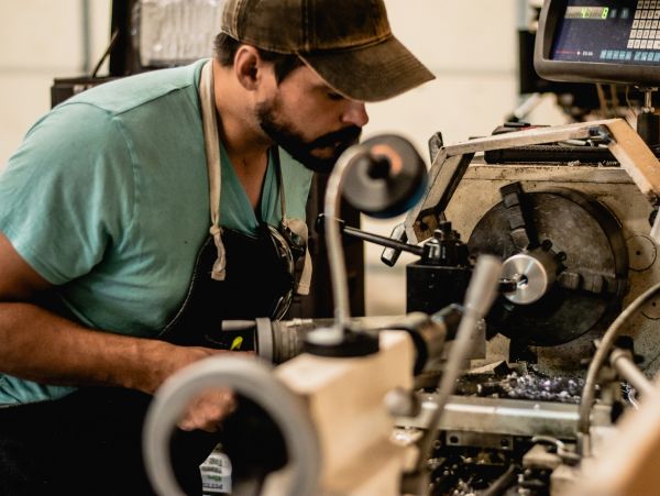 Man operating a lathe machine in a workshop.