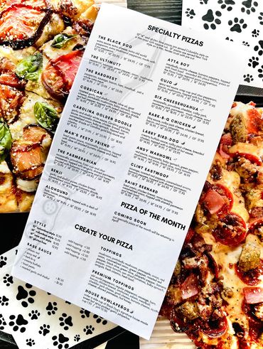 A pizza menu sitting on top of two pizzas.  