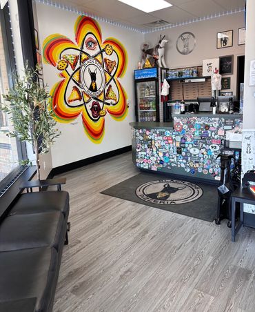 The front lobby of the shop featuring a logo rug, the front counter and a mural on the back wall.  