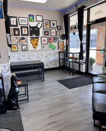 The front lobby of the shop with two dining tables and an art gallery wall.  
