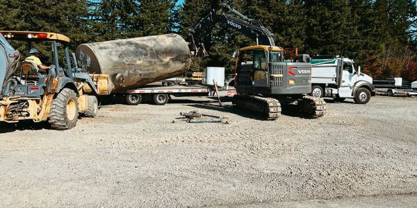 Construction site with heavy machinery and a large cylindrical tank.