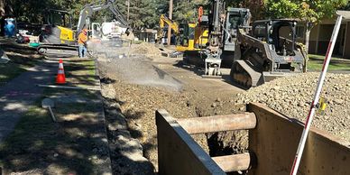 Road construction with heavy machinery and workers on a residential street.