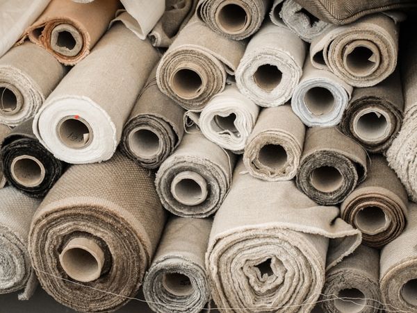 Rolled-up fabric in neutral tones stacked together.