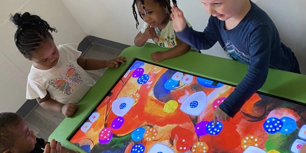 Children interacting with a colorful digital touchscreen table.