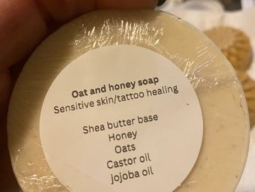 Handheld oat and honey soap wrapped in plastic with healing ingredients.