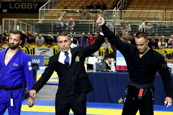 Referee raising the winner's hand in a martial arts competition.