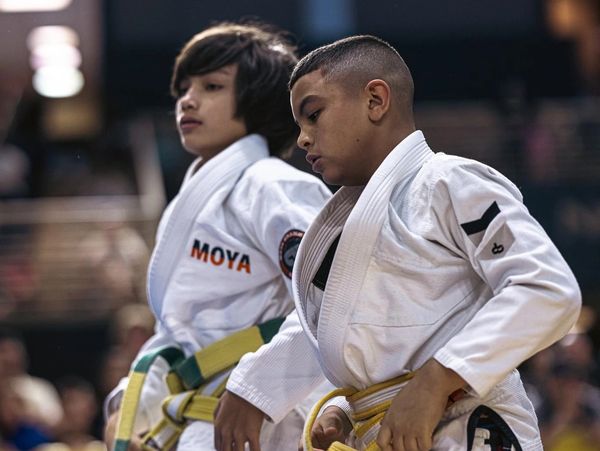 Two young boys in white martial arts uniforms with yellow belts.