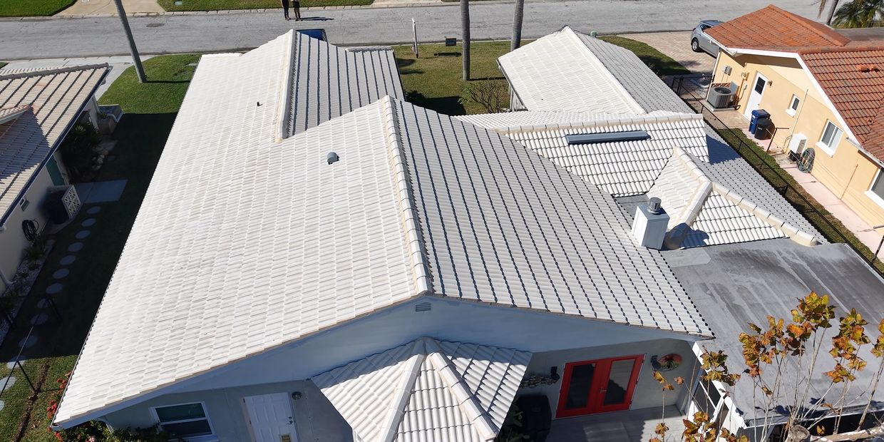 A drone shot of an white tiled roof under a clear blue sky.