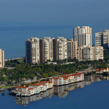 High-rise buildings by a calm waterfront with reflections.