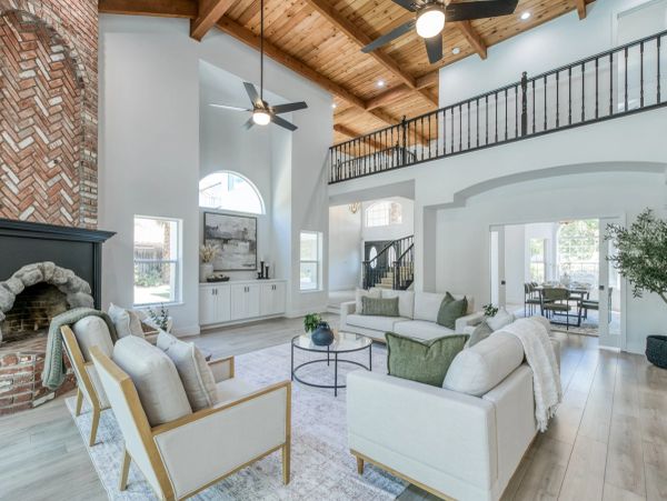 Bright living room with vaulted wood ceiling and brick fireplace.