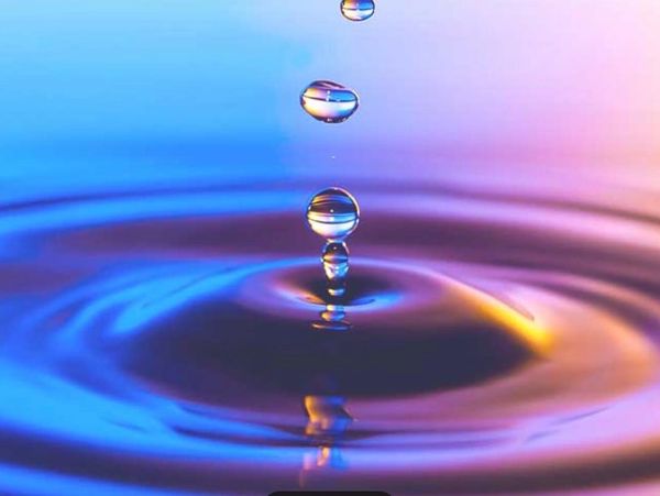 Close-up of water droplets creating ripples with colorful reflections.
