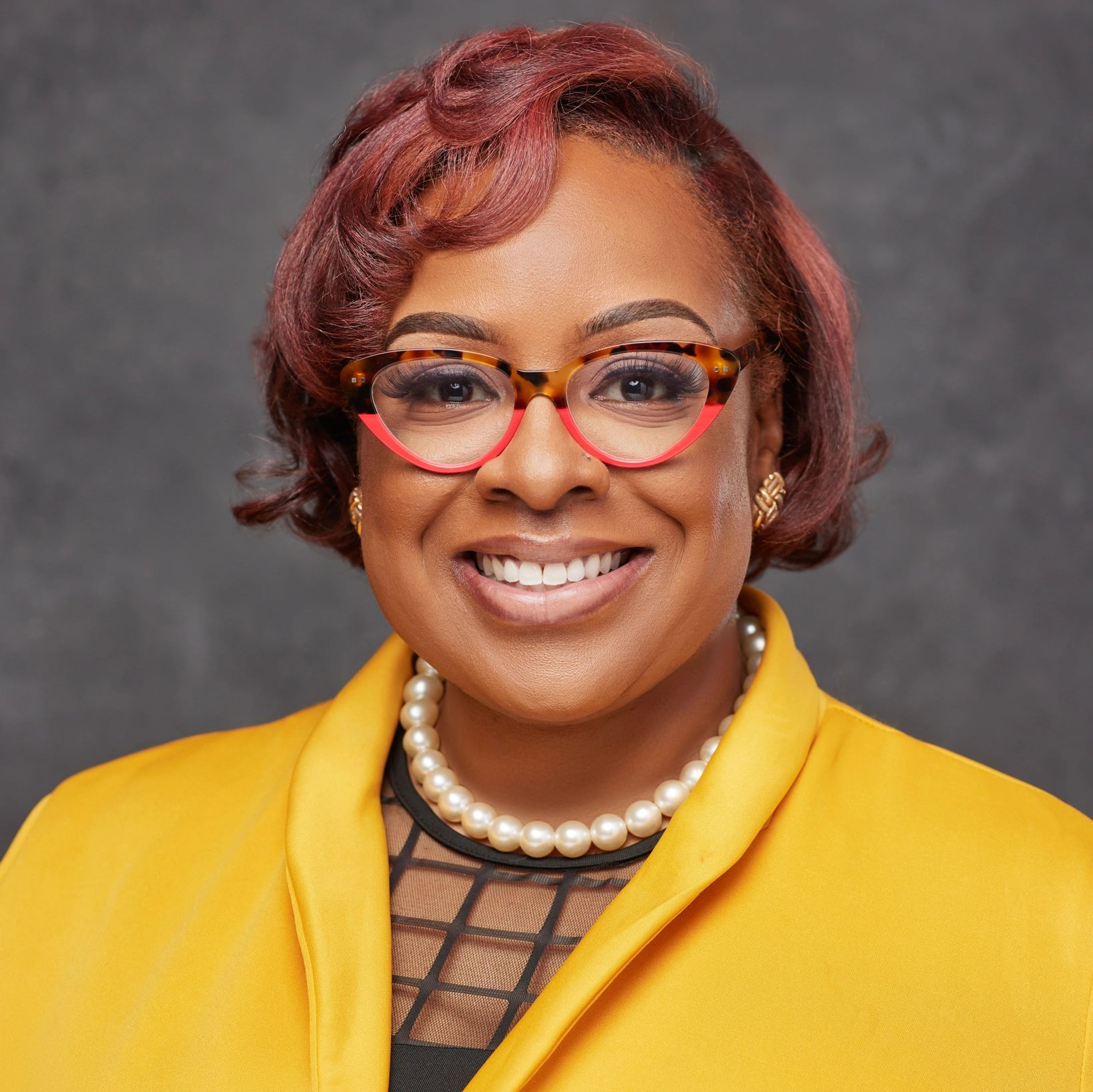 Smiling woman with red hair and colorful glasses.