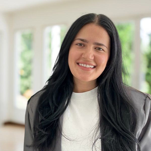 Smiling woman with long black hair indoors.