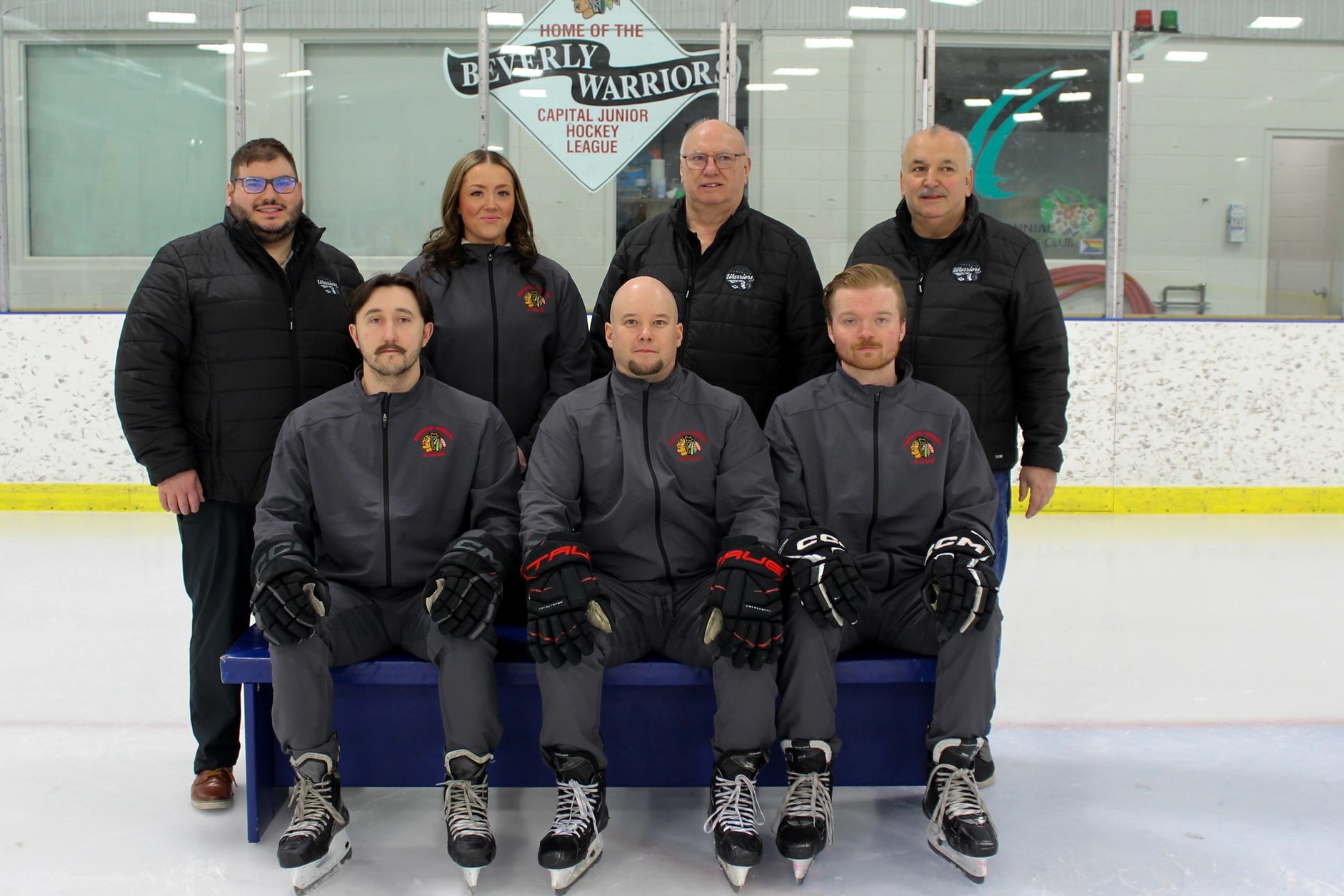 Ice hockey team posing on the rink bench.