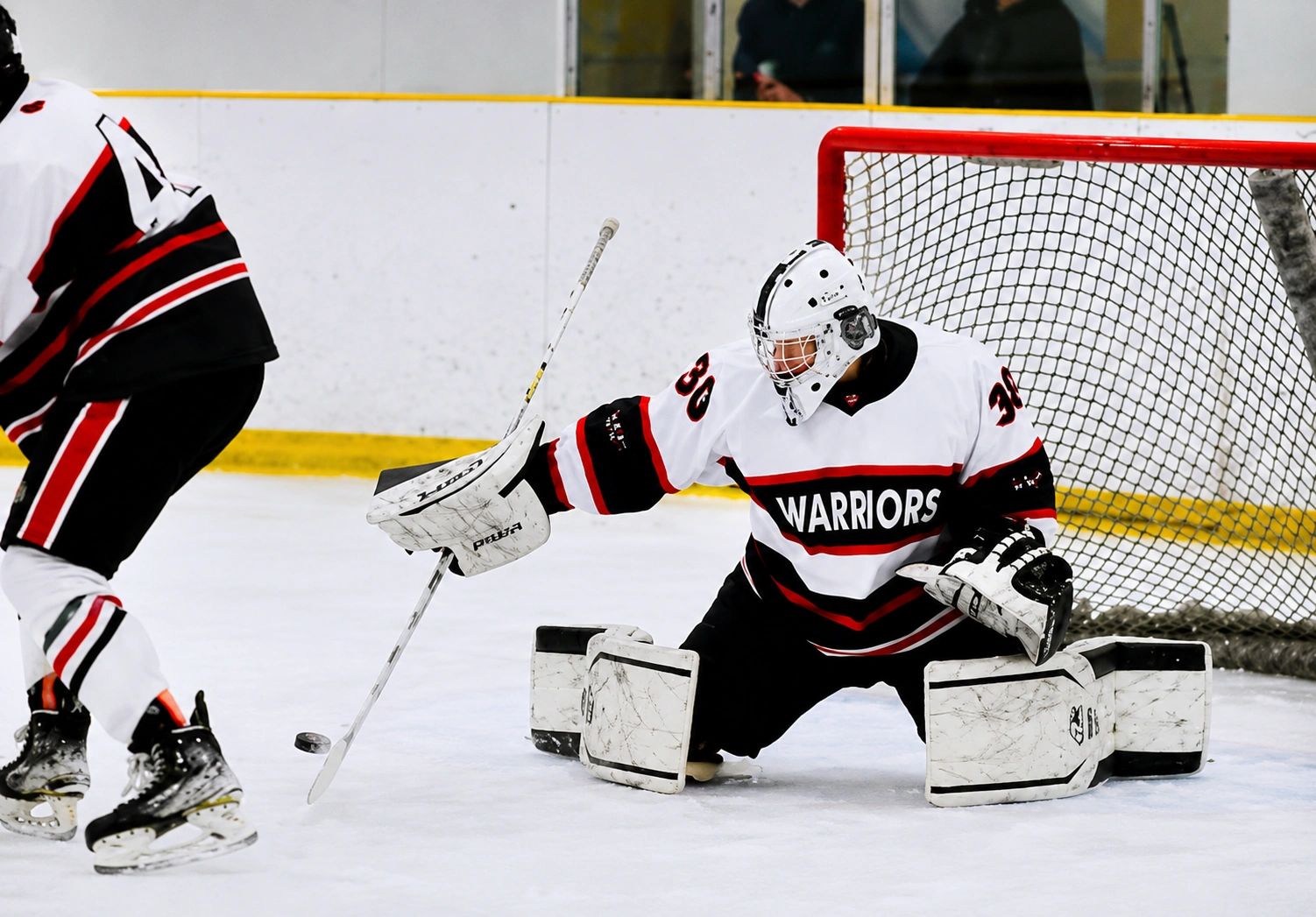 Hockey goalie making a save in front of the net.