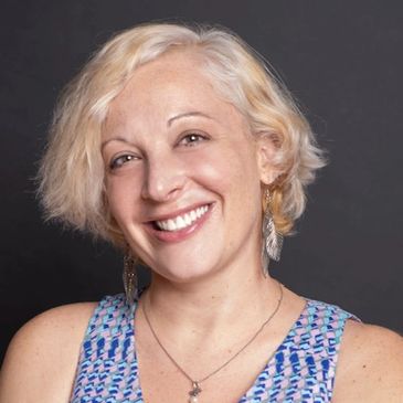 Smiling woman with short blonde hair against a black background.