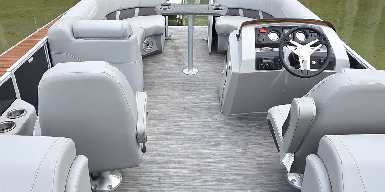 Interior view of a modern pontoon boat with seating and steering wheel.