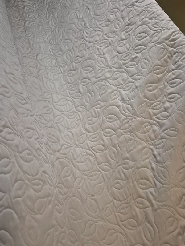 Close-up of a fabric with intricate leaf-patterned quilting.