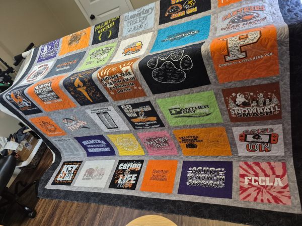 A colorful quilt made of various event T-shirts and memorabilia squares.