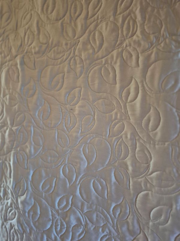 Close-up of a quilted fabric with leaf patterns.