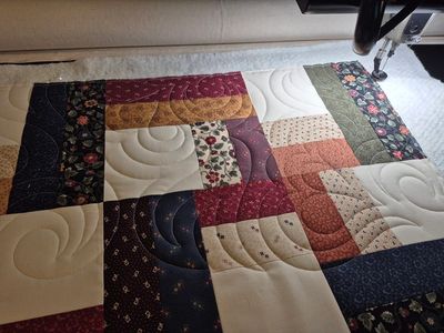 Close-up of a patchwork quilt with various fabric patterns and colors.
