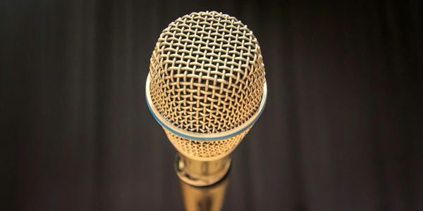 Close-up of a golden microphone against a dark background.