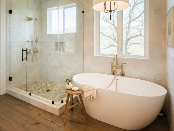Bright bathroom with a freestanding tub and glass shower enclosure.