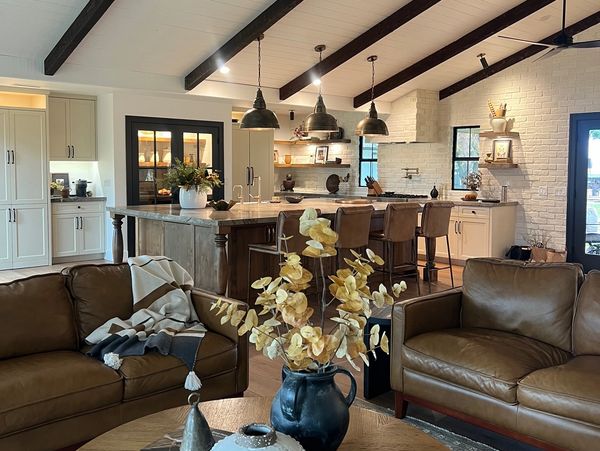 Cozy modern kitchen and living room with leather sofas and rustic decor.