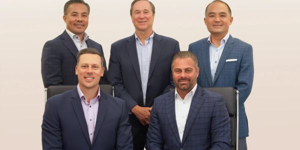Five men in business attire posing for a group photo.