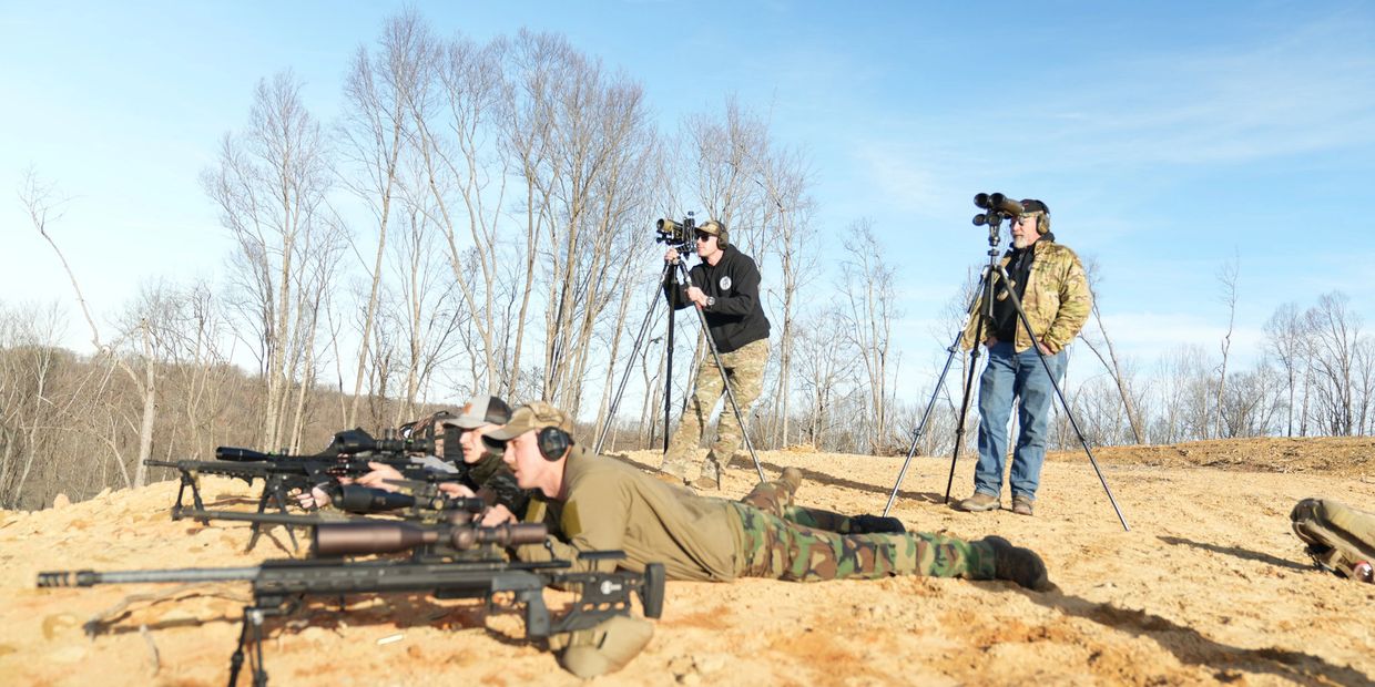 Soldiers aiming rifles while others observe with scopes.