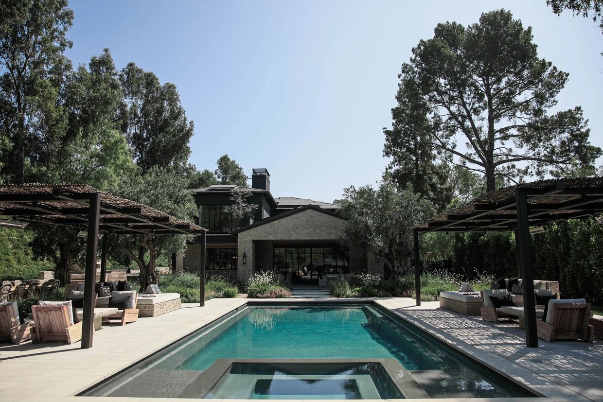 Luxurious backyard with a swimming pool, shaded seating, and lush greenery.
