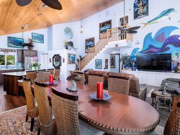 Spacious coastal-themed dining and living area with wooden ceiling and ocean artwork.