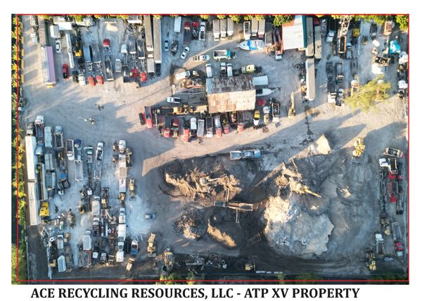 Aerial view of a recycling or construction yard with numerous vehicles and a large excavation.