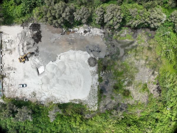 Aerial view of a construction site with machinery and greenery.