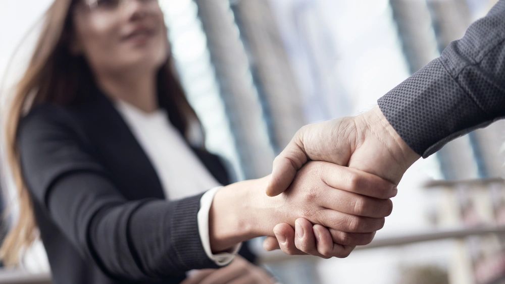 Two people shaking hands in a professional setting.