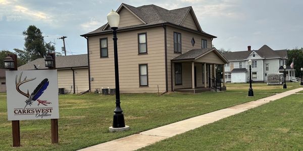 Large beige house with a sign for Carr's West Outfitters.