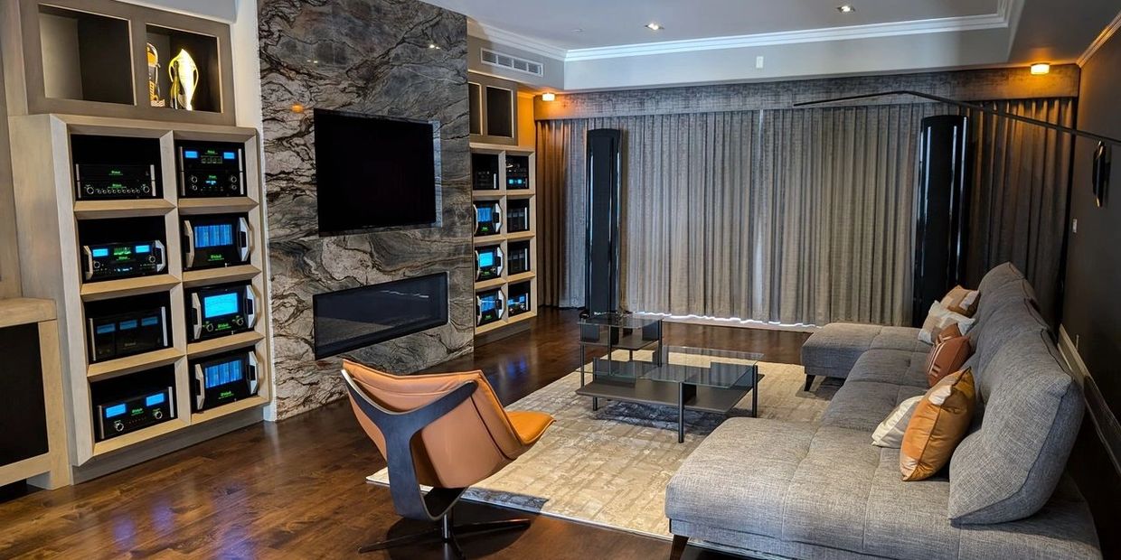 Modern living room with gray sofa, leather chair, and built-in audio system.