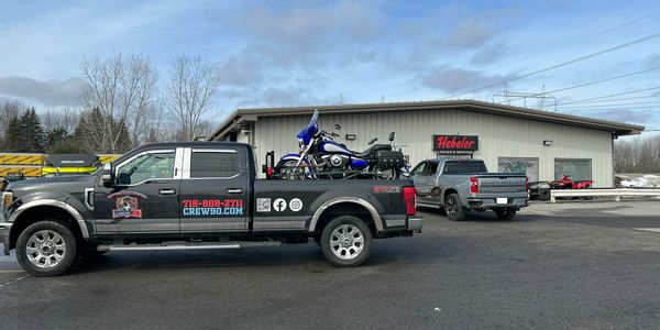 Pickup trucks parked outside a Hebeler Motorsports building on a clear day.