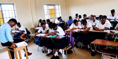 Students in uniform attentively taking a classroom exam.