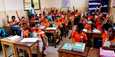Students in a vibrant classroom eagerly participate by raising their hands.