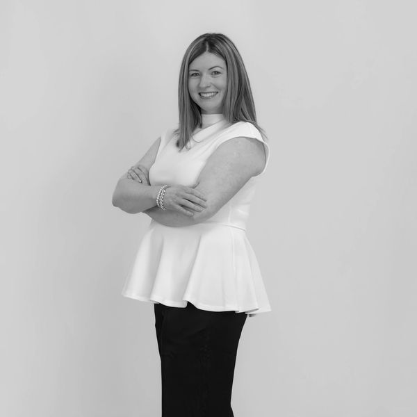 Woman standing with arms crossed, smiling.