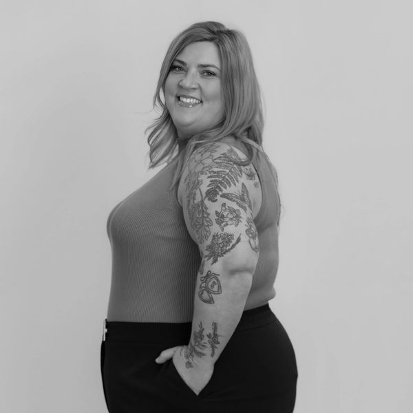Smiling woman with floral tattoos on her arm.