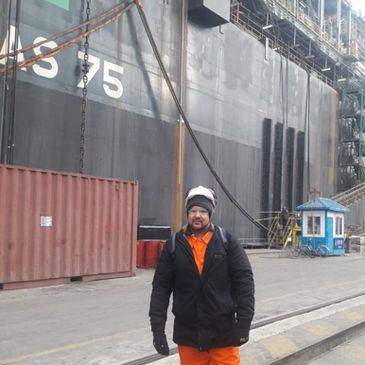 Homem vestindo roupas laranjas e pretas em um porto.
